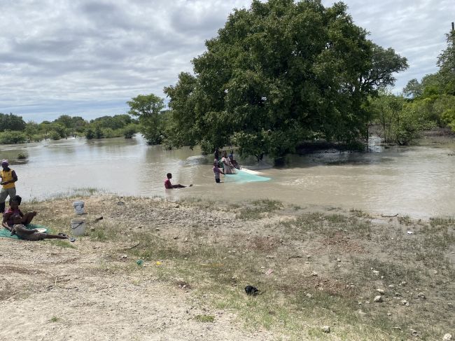 2/4/23.  In Angola, driving north from Namibia border. These locals were fishing for teeney fish being flushed out from a culvert.  

