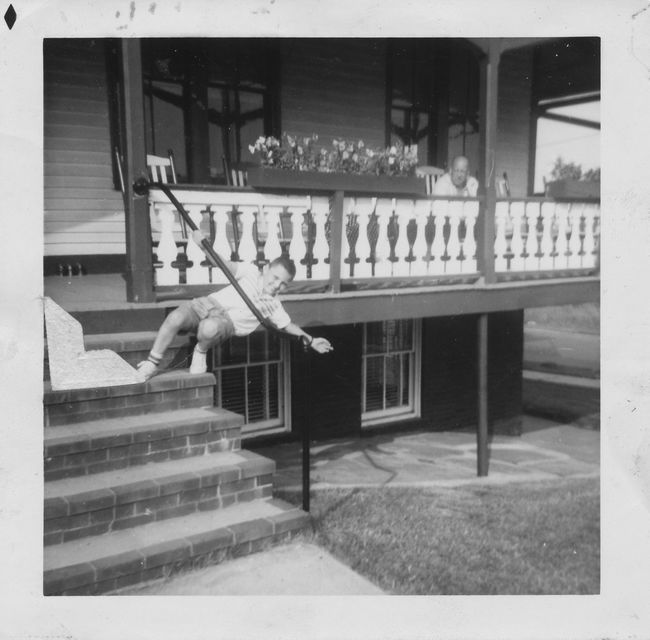 Young Paul Niel hanging from unknown building with unknown man on porch
