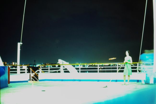 Helen playing shuffleboard on the ship's deck at night
